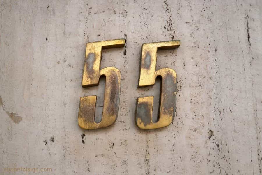 Angel number 55 meaning: A number 55 in brass on a marble façade.
