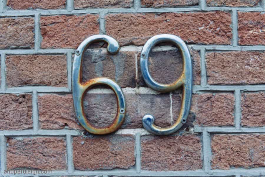 House number 69 on grunge bricks with rust