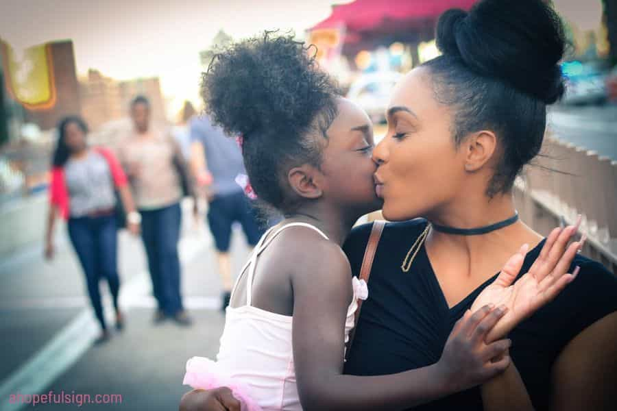 African American woman carrying and kissing a little girl