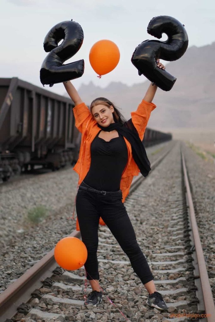 Female model holding inflatable balloons in shape of number 22