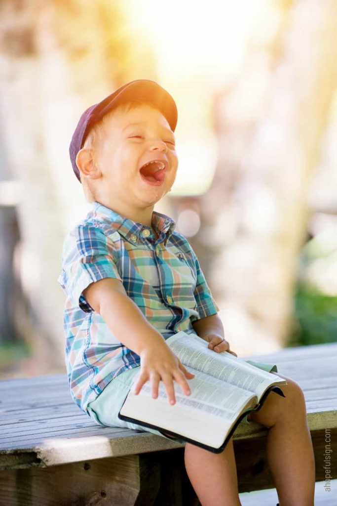 Young boy laughing with a Bible