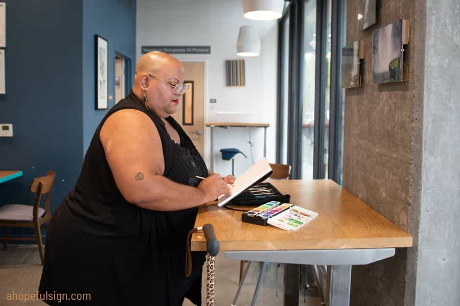 Black non-binary person sits and work an adjustable desk