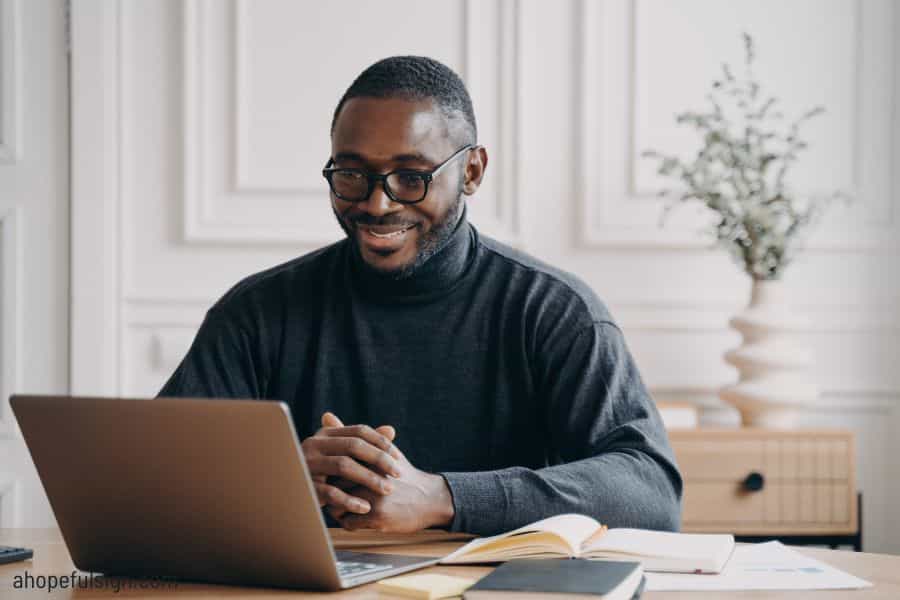 Positive African American male private consultant working on laptop