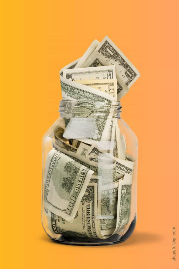 US banknotes in a glass jar on orange background