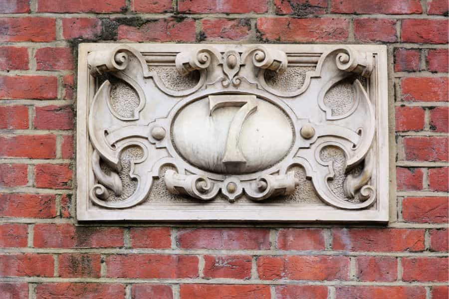 Vintage home number made of stone on a brick wall.