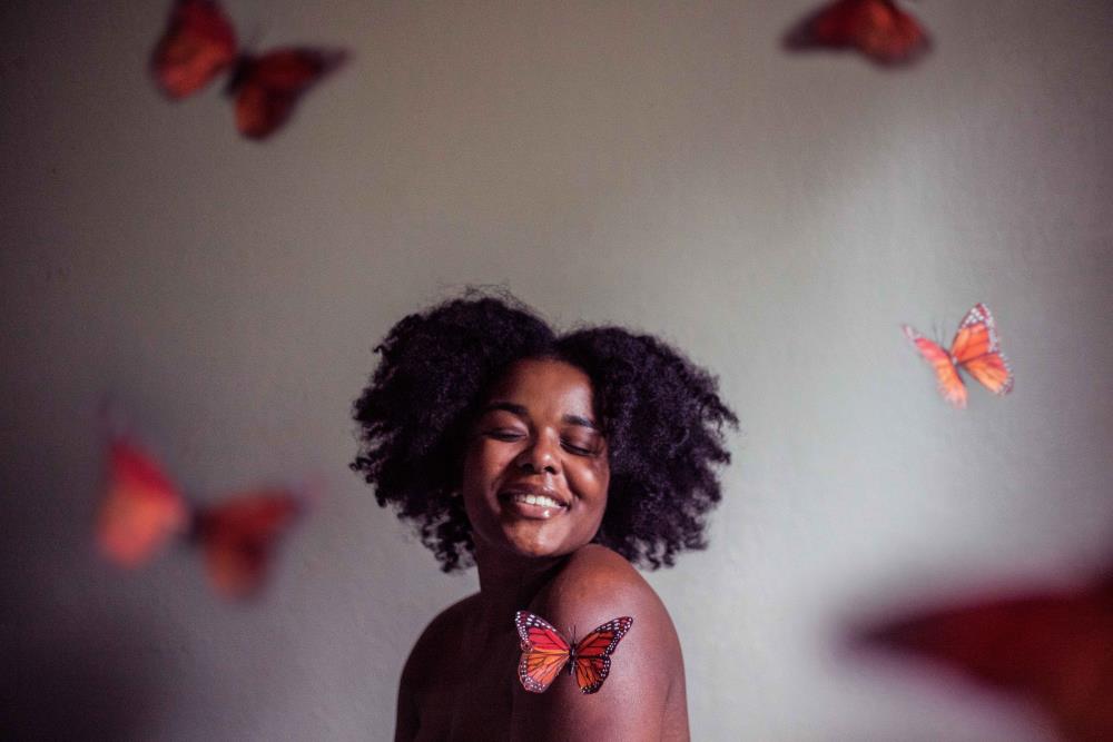African American woman with orange butterflies flying around her