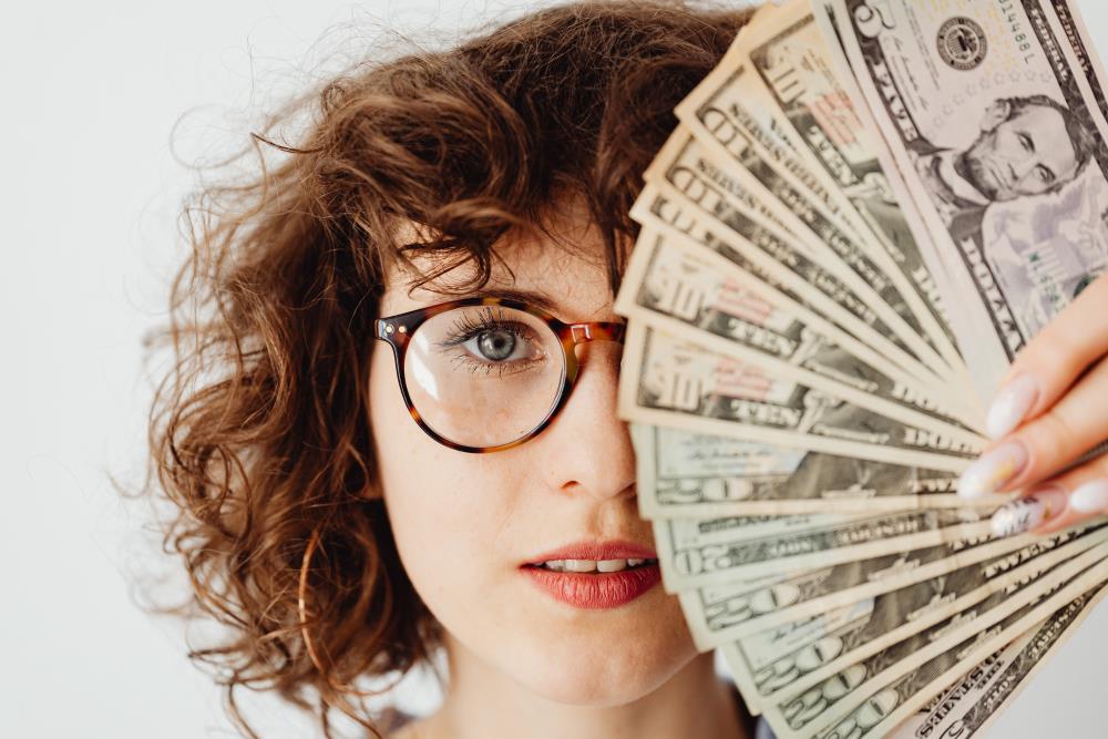 Woman covering her left eyes with banknotes