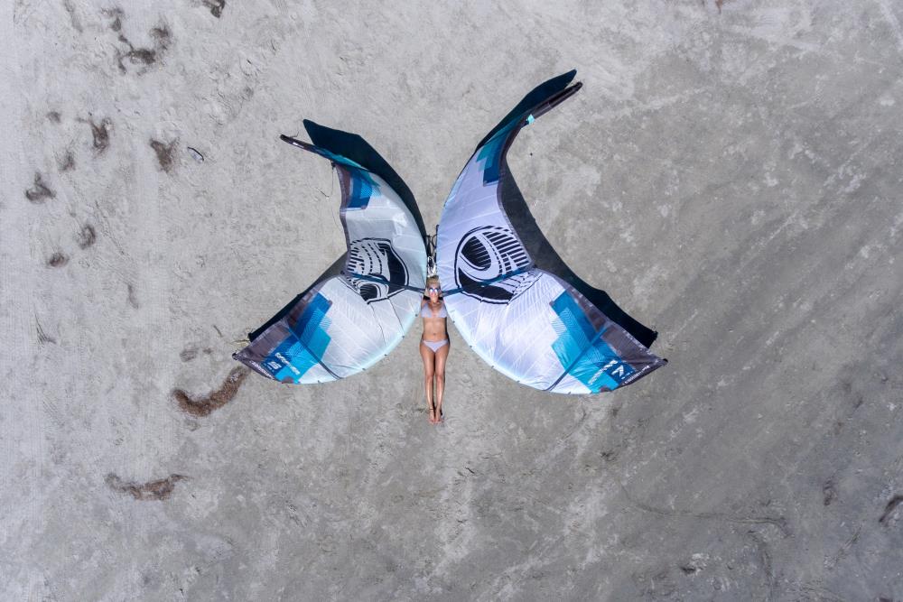 Woman on the beach with 2 windsails representing a blue butterfly